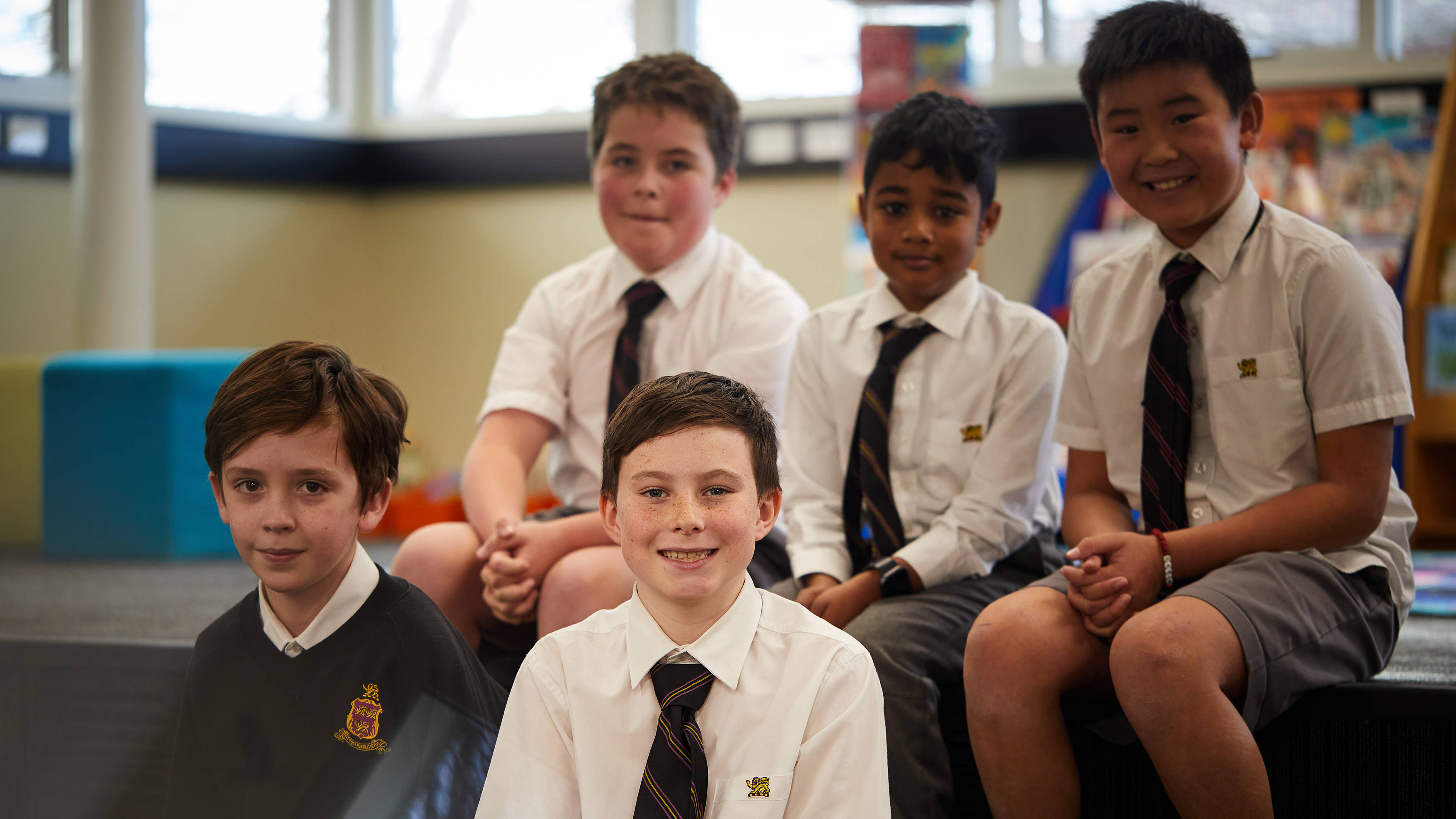 Five smiling Junior School students in the library. Photo: Joshua Lamont.