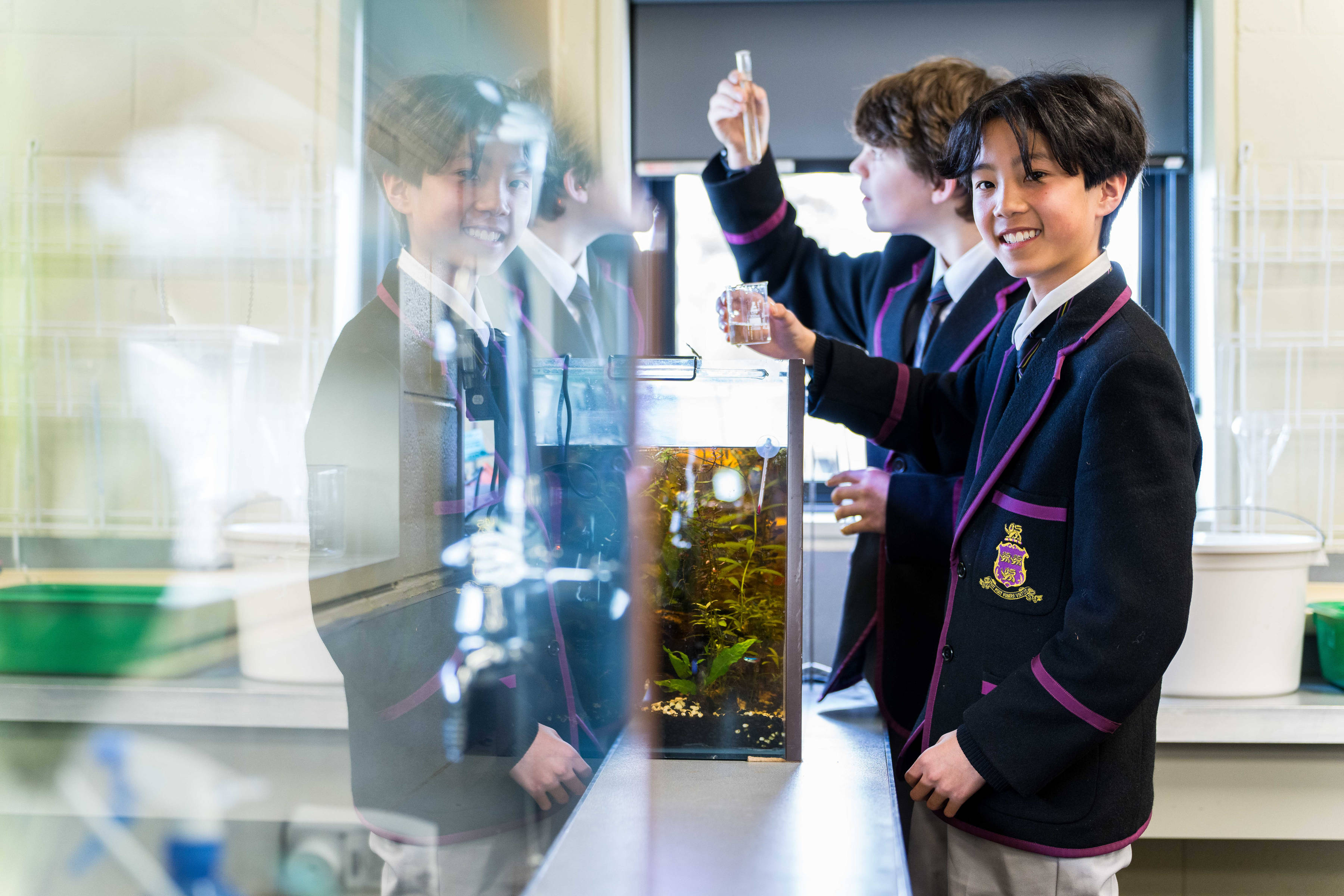 Two Hutchins students in a science class taking water samples from a tank containing aquatic plants.