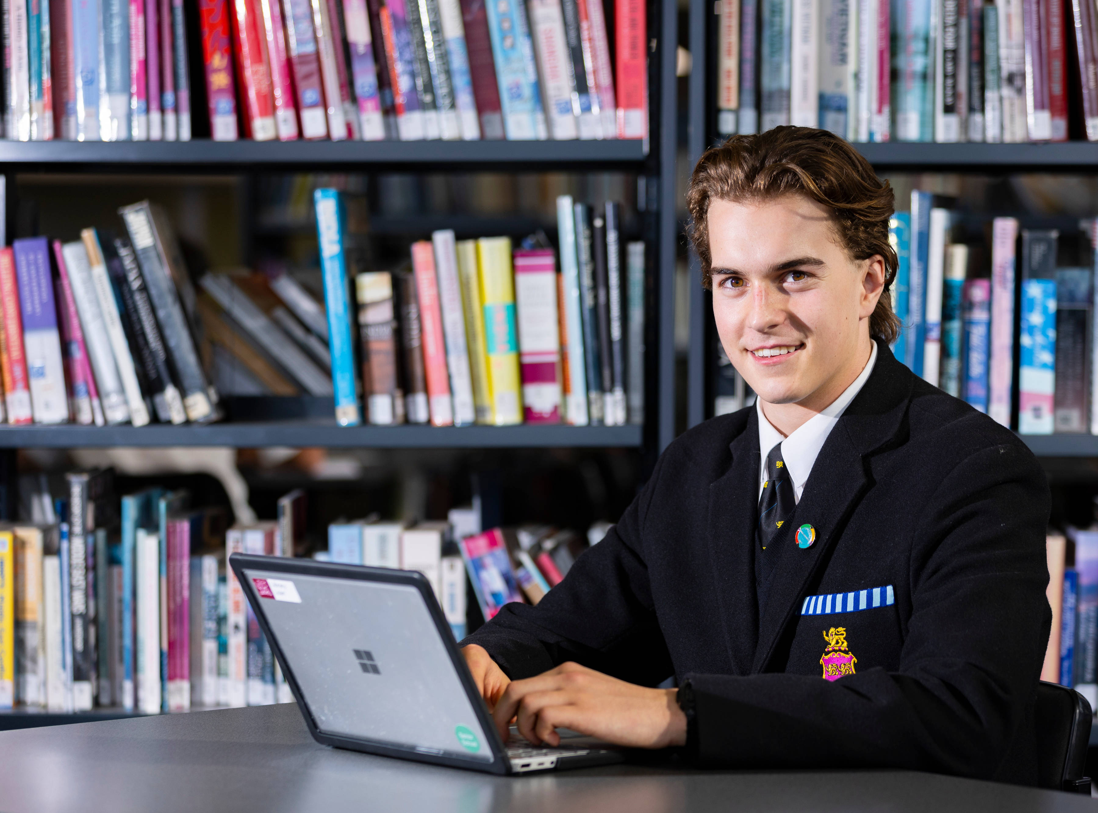 Senior School student working on a laptop computer in a library.